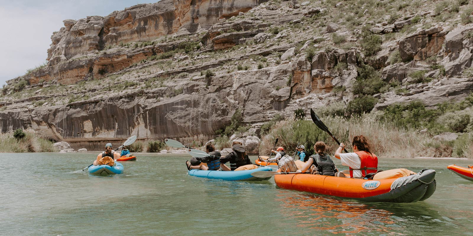 A group of people paddling in kayaks on a river at Camp Cho-Yeh, enjoying outdoor activities.