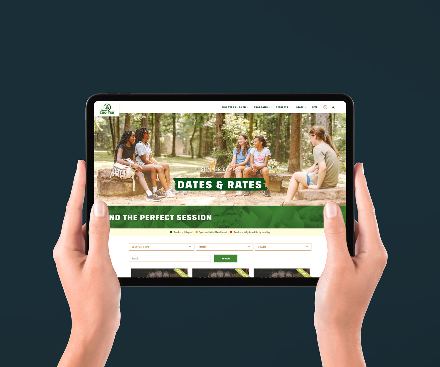 Hands holding a tablet displaying a camp website. The screen shows a "Dates & Rates" page with images of people sitting outdoors and a session search bar.